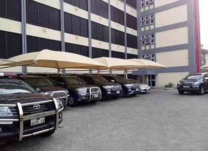 A row of cream cantilever shade canopies covering pickups and four-wheel drives outside an office block