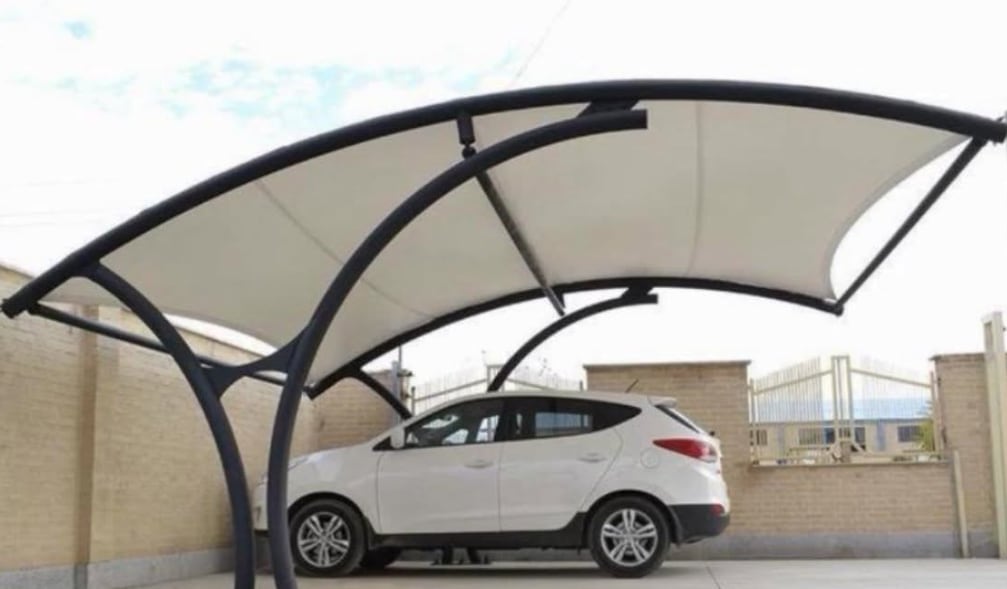 A double arched carport with tensioned white fabric on a dark steel frame, covering a white SUV